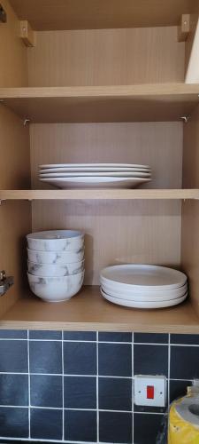 a kitchen shelf with plates and bowls on it at 13 Decent Homes in Dukinfield