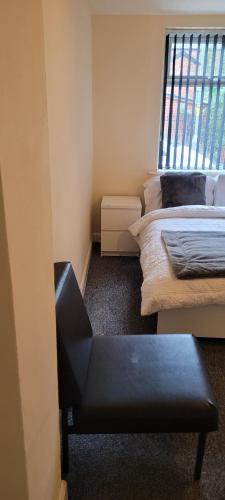 a room with two beds and a black bench in it at 13 Decent Homes in Dukinfield