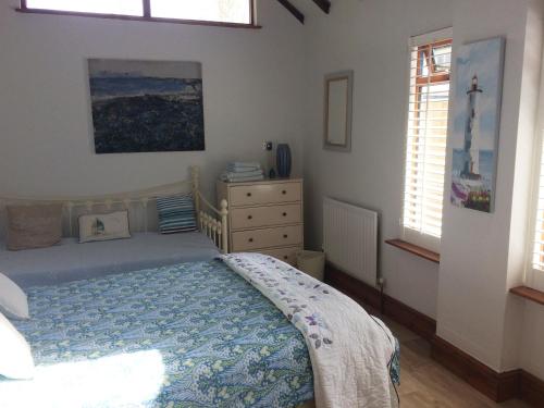 ein Schlafzimmer mit einem Bett, einer Kommode und zwei Fenstern in der Unterkunft The Swallows in Appledore