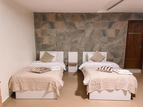 Habitación con 2 camas y pared de piedra. en Sky Suites East Legon en Accra
