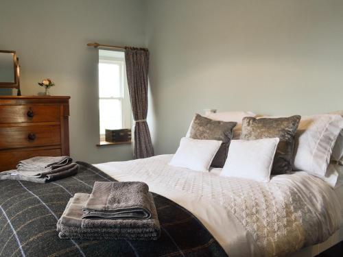 a bedroom with a large bed with a dresser and a window at Porthysgaden in Twdweiliog