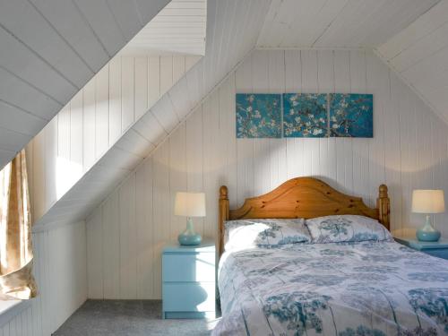 a bedroom with a bed with two lamps and a window at Shore Cottage in Arnisdale