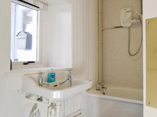 a white bathroom with a sink and a shower at Shore Cottage in Arnisdale