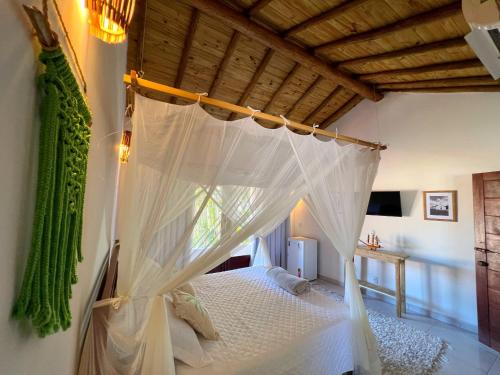 um quarto com uma cama de dossel branca em Casa Roure Pousada em Trancoso