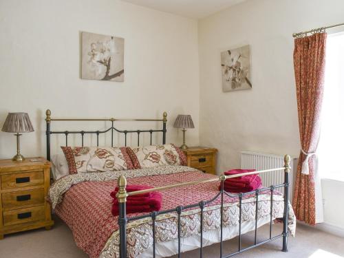 Schlafzimmer mit einem Bett mit einer roten Bettdecke in der Unterkunft Poppy Cottage in Buckden