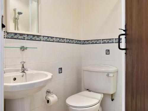 a bathroom with a white toilet and a sink at Poppy Cottage in Buckden