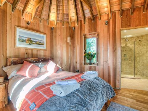a bedroom with a bed in a room with wooden walls at Trewalter Treehouse in Brecon