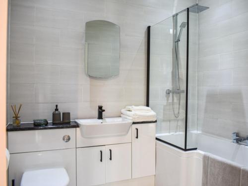 a white bathroom with a sink and a shower at Watersreach in Collieston