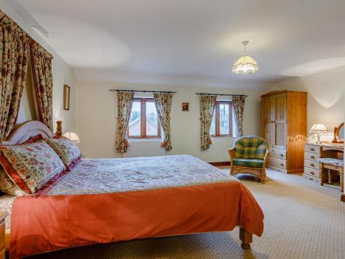 um quarto com uma cama, uma cadeira e janelas em Purlin Barn - E3867 em Runcton Holme