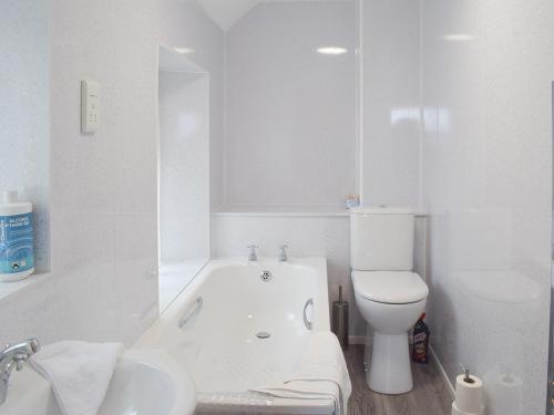 baño blanco con bañera y aseo en Ardlochan Cottage, en Maidens