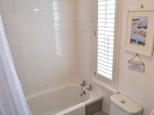 La salle de bains blanche est pourvue d'une baignoire et de toilettes. dans l'établissement Sandhills, à Sea Palling