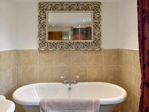 a bathroom with a tub and a mirror at Bumblebee Nook in Penrith