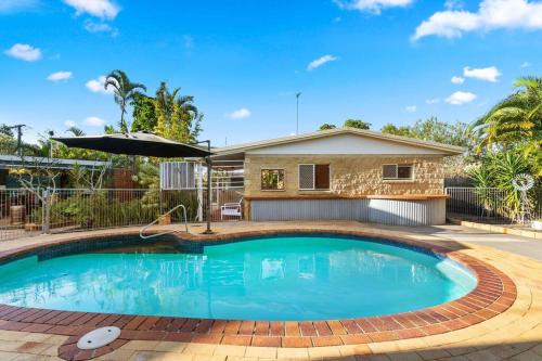a swimming pool in front of a house at Relaxed Urangan Living at the Poolside Bungalow in Hervey Bay