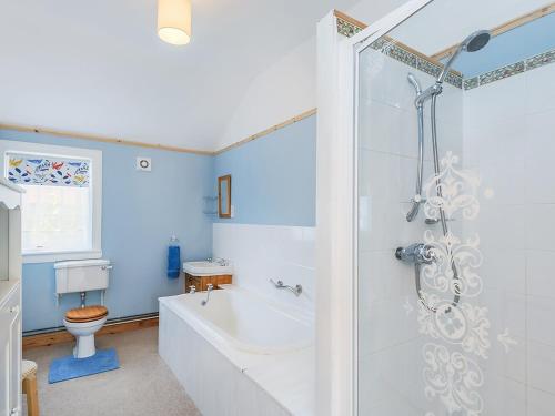 a bathroom with a tub and a toilet and a sink at Lucklaw Steading Cottage in Logie