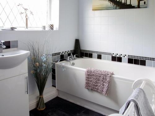 a white bathroom with a tub and a sink at Archways-e1223 in Winthorpe