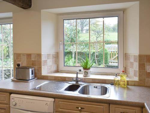 a kitchen with a sink and a window at Drumlins Cottage in Gatebeck
