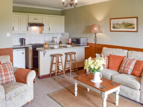 a kitchen and living room with a couch and a table at Prior Dene Cottage in Staintondale