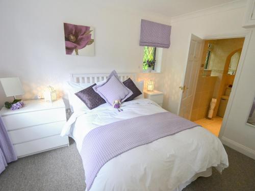 a bedroom with a white bed with purple pillows at Alices Lodge in Ringwood