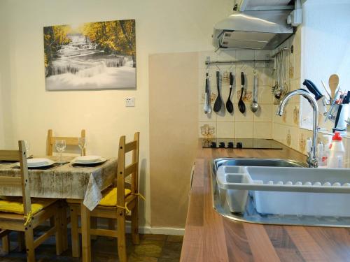 a kitchen with a sink and a table at Castiel Cottage in Yspytty-Ifan