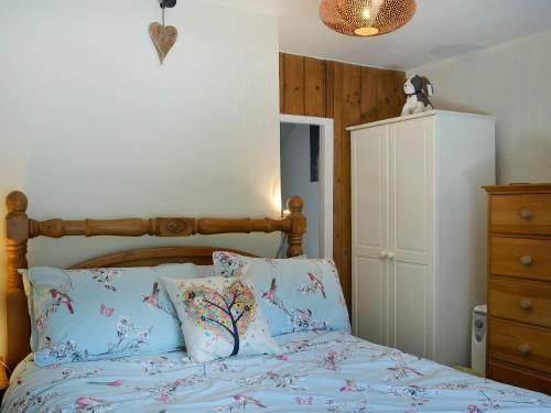 a bedroom with a bed with a wooden headboard and pillows at Castiel Cottage in Yspytty-Ifan
