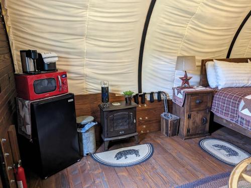 a room with a bed and a stove in a tent at Rooterville Animal Sanctuary in Melrose