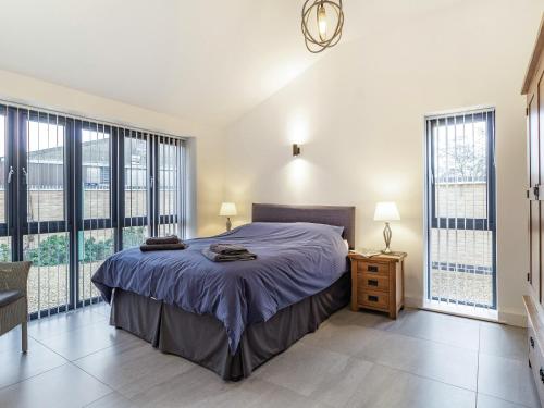 a bedroom with a large bed and large windows at Fenside Way in Wicken