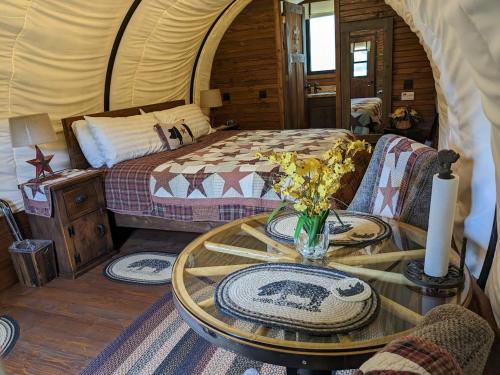 Un dormitorio con una cama y una mesa con un jarrón de flores en Rooterville Animal Sanctuary, en Melrose