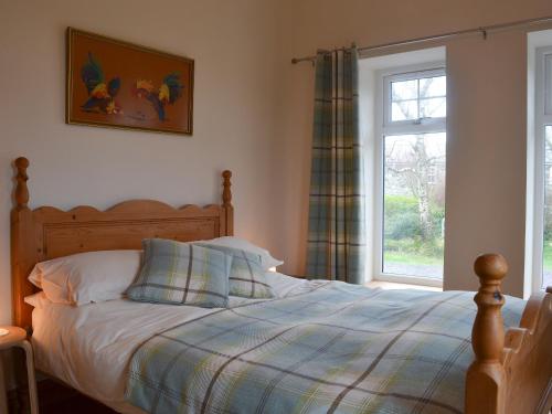 una camera da letto con un letto con una coperta scozzese e una finestra di Crib Y Nantlle a Llandwrog