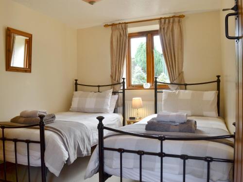 a bedroom with two beds and a window at Higher Hopworthy Cottage-uk11436 in Pyworthy