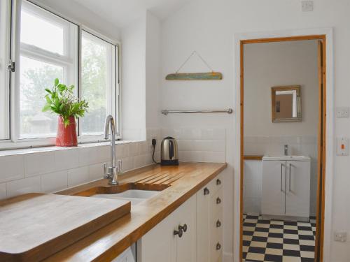 a white kitchen with a sink and a window at Elm Cottage in Whitwell