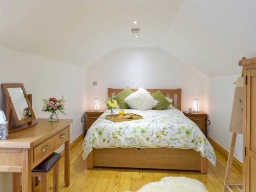 a bedroom with a bed with a dresser and a mirror at Snowdrop Cottage - Uk12987 in Monington