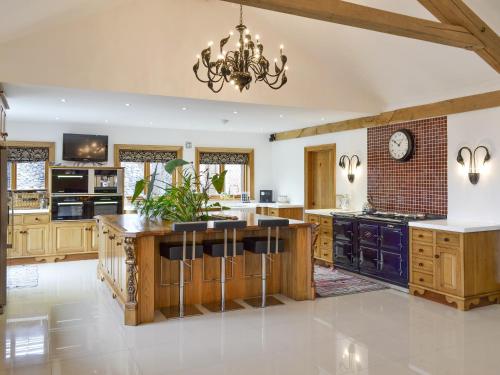 a large kitchen with wooden cabinets and a chandelier at Carr End Barn A in Preesall