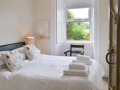 Un dormitorio con una cama blanca con toallas. en Prudhoe Mews, en Alnmouth