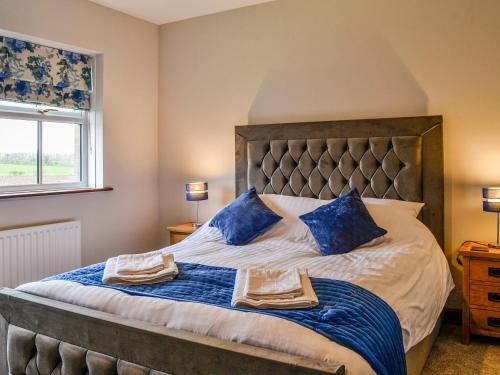ein Schlafzimmer mit einem großen Bett mit blauen Kissen in der Unterkunft Ellerton Croft in Wreay