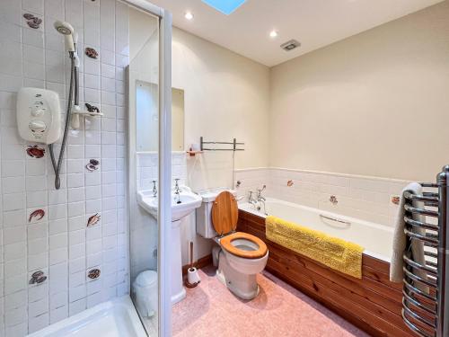 a bathroom with a toilet and a sink and a tub at The Old Post Office in Arnisdale