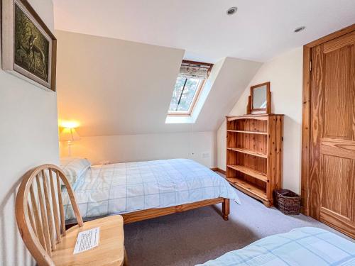 a bedroom with a bed and a chair and a window at The Old Post Office in Arnisdale