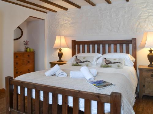 ein Schlafzimmer mit einem großen Bett mit zwei Enten auf den Kissen in der Unterkunft The Old Coach House in Woolfardisworthy