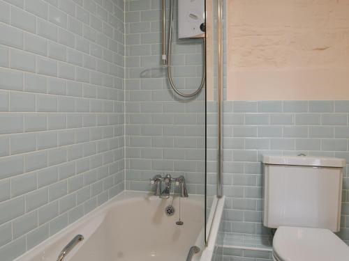 La salle de bains est pourvue d'une baignoire blanche et de toilettes. dans l'établissement The Old Coach House, à Woolfardisworthy
