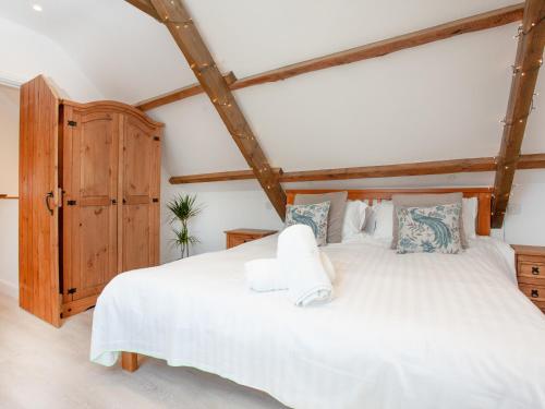 a bedroom with a large white bed with wooden beams at The Shippon - Uk37467 in Berrynarbor