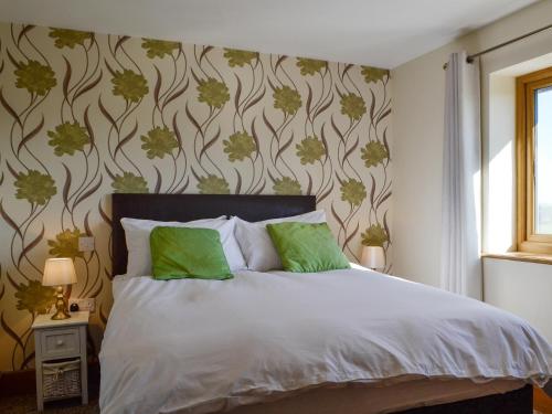 a bedroom with a bed with green pillows at Upper Close in Evenjobb