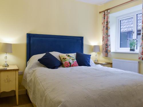 a bedroom with a large bed with a blue headboard at Th Hollow in Bishops Lydeard