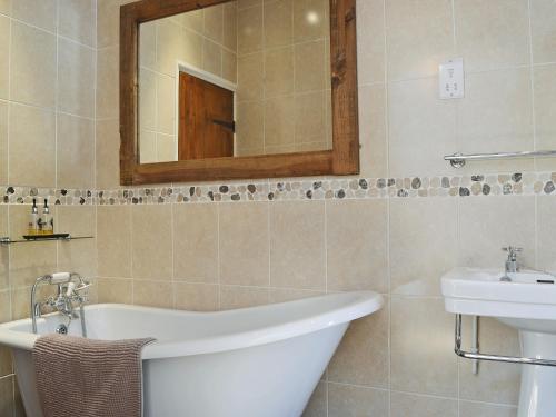 a bathroom with a tub and a sink and a mirror at Walkmill Lodge in Wentnor