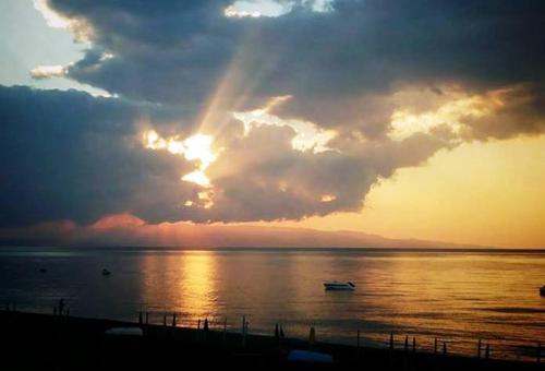 a sunset over the ocean with a boat in the water at Colapesce in Santa Teresa di Riva