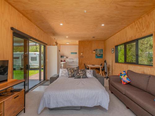 a bedroom with a bed and a couch at Whangapoua Hideaway - Whangapoua Bach in Whangapoua