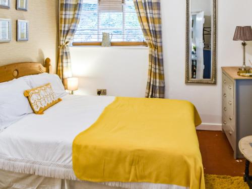 a bedroom with a bed with a yellow blanket at Lower West in Newnham