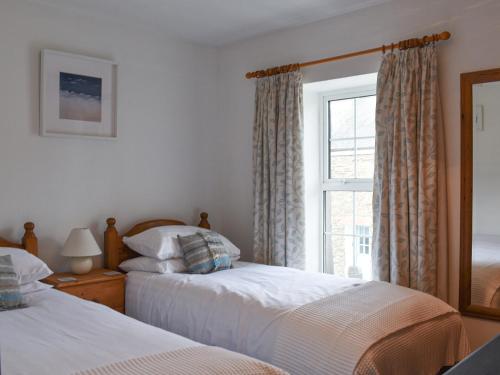 - une chambre avec 2 lits et une fenêtre dans l'établissement Squirrel Cottage, à Wadebridge