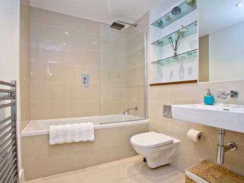 a bathroom with a toilet and a tub and a sink at 9 The Whitehouse in Mawgan Porth