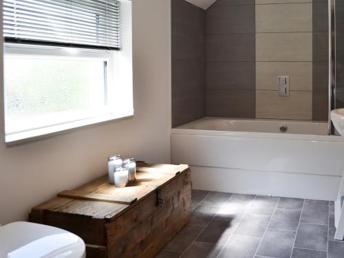 a bathroom with a bath tub and a toilet and a wooden box at Dragonfly Cottage in Beverley