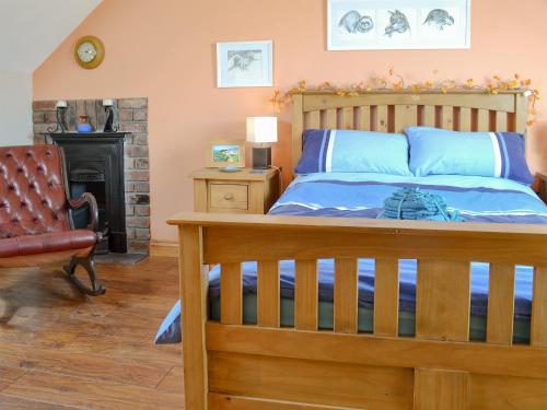 a bedroom with a wooden bed and a chair at Hen Dy Goits in Llangadwaladr