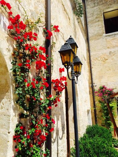two street lights with red flowers on a wall at Castello Conti Filo in Torre Santa Susanna